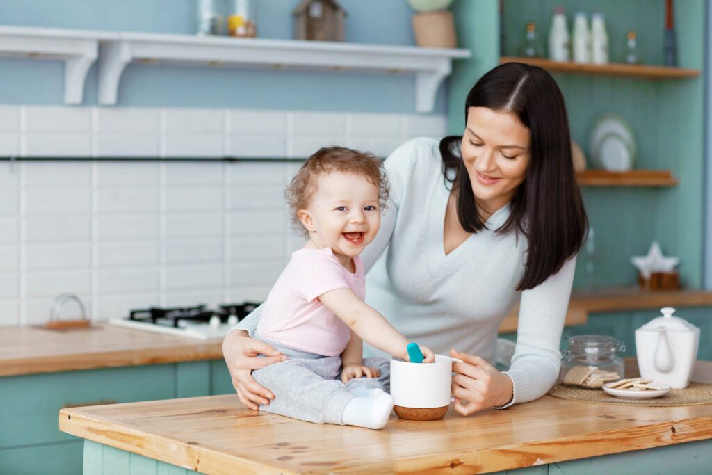 happy-baby-sitting-on-the-kitchen-table-with-mom-s-K5D9ELD.jpg